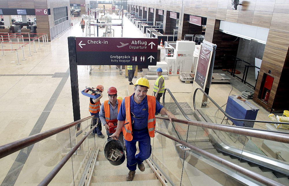 Celtnieki Berlīnes-Brandenburgas lidostas iekštelpās. Lidostu atklāja 2020. gadā, taču tās būve vēsturē palikusi kā "katastrofa visos līmeņos".