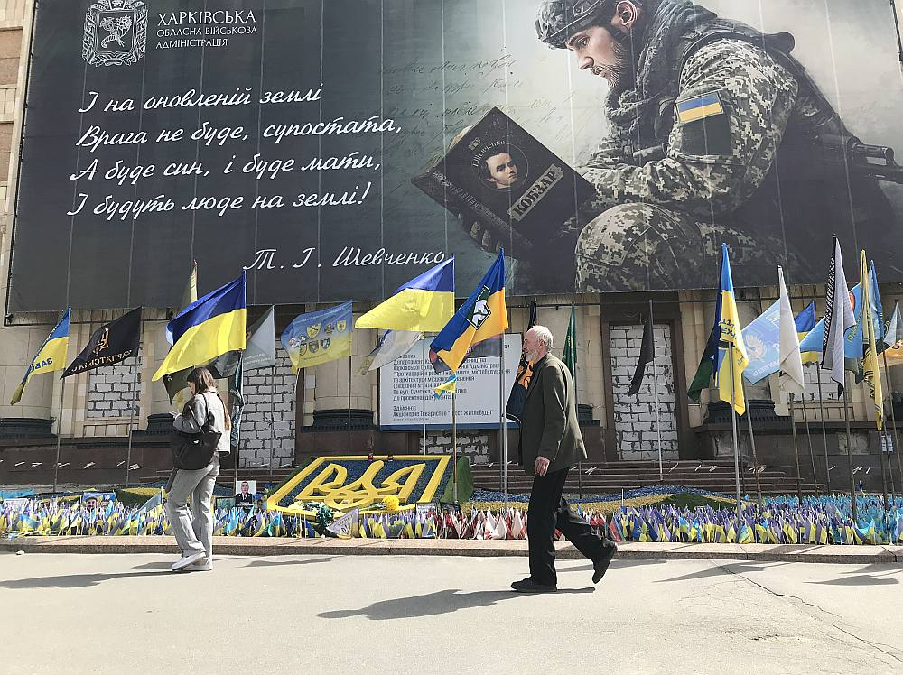 Plakāts pie Harkivas apgabala administrācijas sagrautās ēkas. Uz tā citētas Tarasa Ševčenko dzejas rindas, kurās vēstīts, ka uz atjaunotās zemes nebūs ienaidnieka, pretinieka, bet būs dēls, māte un cilvēki...