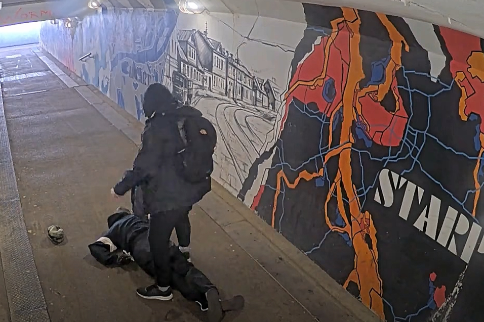 Agresīvais vīrietis stāv pie piekautā vīrieša.