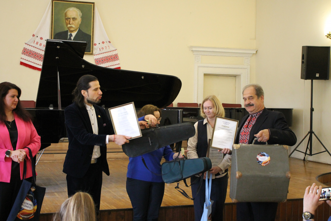 Pianists Andrejs Osokins un nodibinājuma “Osokinu fonds” vadītāja Daiga Bināne pasniedz Čerņihivas apgabala mūzikas skolu pārstāvjiem akcijas “Nosūti mūziku Ukrainai” laikā ziedotos mūzikas instrumentus, kurus turpmāk izmantos apgabala mūzikas skolu audzēkņi.