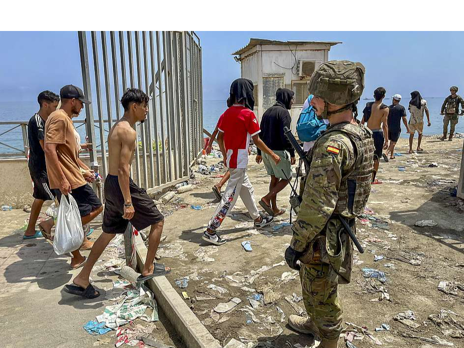 Spānijas karavīrs noraugās, kā no Marokas puses atpeldējušie migranti 31. jūlijā ierodas Seutā.