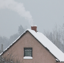 Māja ar kūpošu skursteni ziemā.