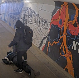 Agresīvais vīrietis stāv pie piekautā vīrieša.