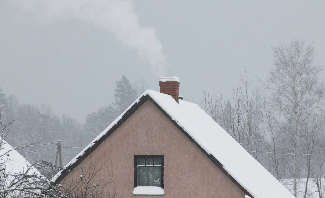 Māja ar kūpošu skursteni ziemā.