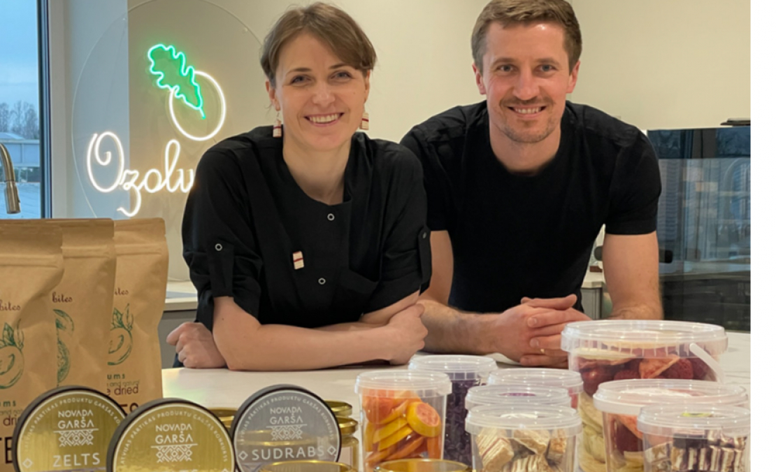 Marta un Intars Ozoli savā jaunajā ražotnē pie lielā darba galda, uz kura izlikts teju viss viņu ražojumu klāsts, kā arī “Novada garšas” konkursā iegūtās godalgas. Priekšplānā – gabaliņos sagrieztā medus kūka.