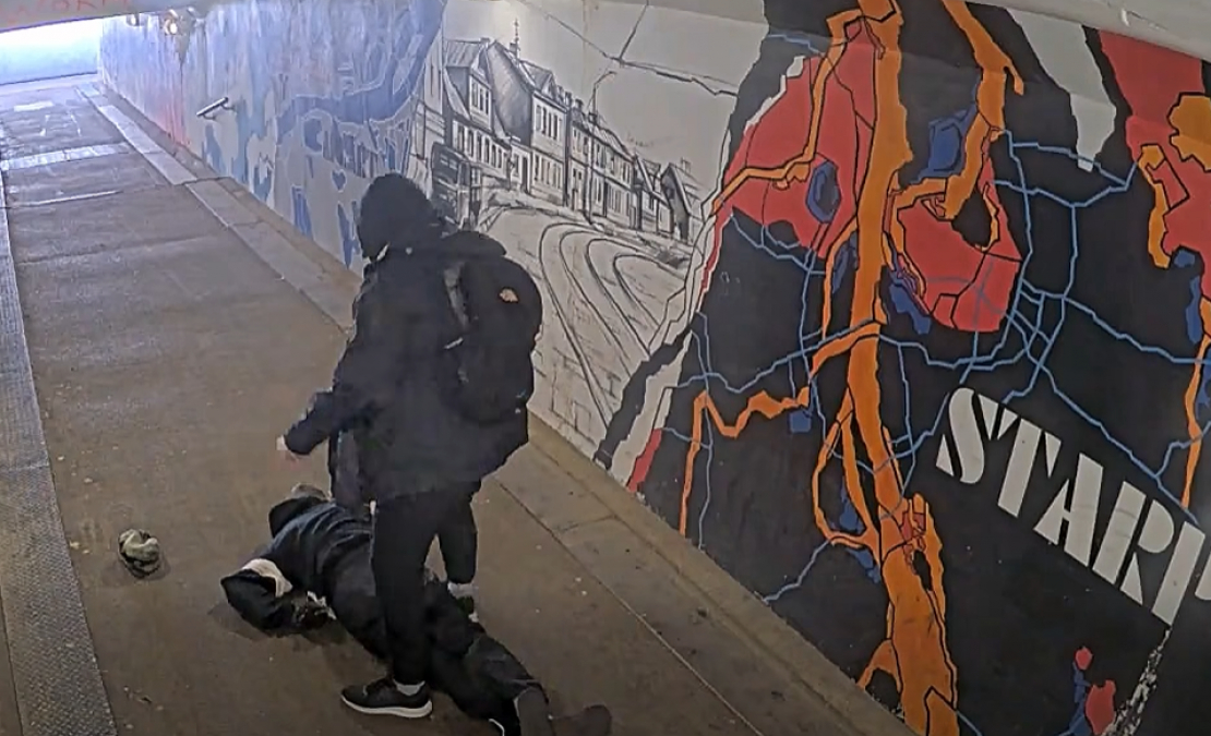 Agresīvais vīrietis stāv pie piekautā vīrieša.