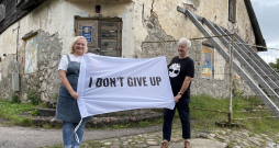 Ieva un Dainis Grozas pie Lēdurgas kroga ieejas ar plakātu, kura teksts angļu valodā vēsta “Es nepadošos”. Esot aizgūts no mākslinieka Kristiana Brektes oriģināla. Ieva un Dainis Grozas pie Lēdurgas kroga ieejas ar plakātu, kura teksts angļu valodā vēsta “Es nepadošos”. Esot aizgūts no mākslinieka Kristiana Brektes oriģināla.