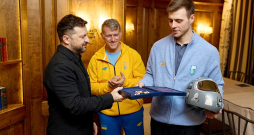Ukrainas prezidents Volodimirs Zelenskis (no kreisās) Minhenes drošības konferencē tikās ar skeletonistu Vladislavu Heraskeviču, pasniedzot viņam Brīvības ordeni. Vidū tēvs un treneris Mihailo Heraskevičs.