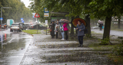 Cilvēki autobusa pieturā negaisa laikā Rīgā.