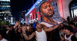 Attēlā redzams Ņujorkas "Knicks" līdzjutējs, kurš 2026. gada 13. jūnijā Ņujorkā tur Džeilena Bransona attēlu.