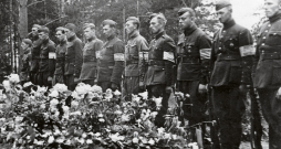 Bijušo Latvijas armijas karavīru un aizsargu – tobrīd Vācijas kārtības
dienesta darbinieku ierinda  pie padomju okupācijas Baigā gada
upuru masu kapa. 1941. gada vasara.