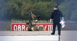Kriminālistikas eksperts strādā līdzās policijas sapieru robotam pie Ukrainas kravas lidmašīnas Leipcigas/Halles lidostā Škeidicā, Vācijas austrumos, 2026. gada 5. augustā. Naktī lidmašīnas tuvumā tika atrasts ar sprāgstvielām aprīkots drons, bet netālu cita lidmašīna gaisā sadūrās ar nezināmu lidojošu objektu un pēc tam droši nolaidās.