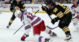Alberts Šmits (no kreisās) arī ar salūzušu nūju un gandrīz jau uz ceļiem cenšas apturēt ripu, lai tā nenonāktu pie Bostonas "Bruins" kapteiņa Davida Pastrņāka.
