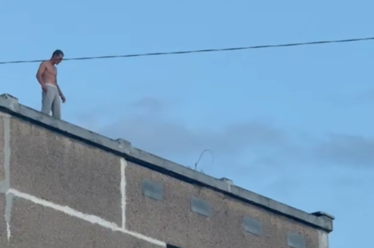 Aizturētais vīrietis uz daudzstāvu mājas jumta. Aizturētais vīrietis uz daudzstāvu mājas jumta.