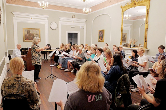 Londonas latviešu koris savā mājvietā – "Daugavas vanagu" fonda Londonas namā. Tur, kur zālē pie sienas piestiprināts Latvijas ģerbonis, vienmēr stāv diriģents.