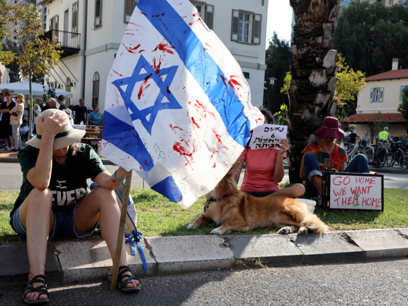 Izraēlas lielpilsētā Telavivā cilvēki ar asiņainu Izraēlas karogu pieprasa, lai valdība panāktu palestīniešu teroristu gūstā nonākušo ķīlnieku atbrīvošanu. Teroristi aizveda sev līdzi vairāk nekā 150 ķīlnieku.