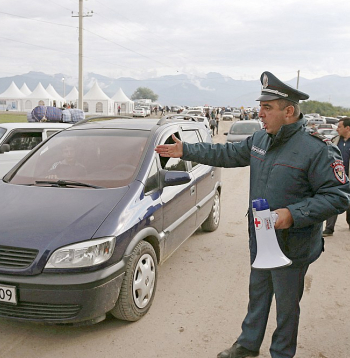 Armēņu policists regulē bēgļu ierašanos Kornidzorā, kas ir Armēnijas un Kalnu Karabahas robežciems. Tur viena pēc otras ierodas ļaužu un mantu pilnas automašīnas.