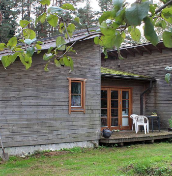 Koka paneļu ēka apšūta ar dēļiem, jumts noklāts ar šindeļiem.