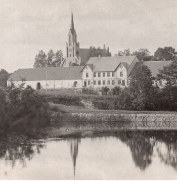 Cesvaines biedrības māja, priekšplānā dzirnavu dīķis, aizmugurē luterāņu baznīca. Fotografēts pirms 1916. gada rudens. Kreisajā pusē kroga stadula, kas pārbūvēta par kultūras veicināšanas biedrības zāli. Labajā pusē jau pirms simt gadiem bijuši veikali.