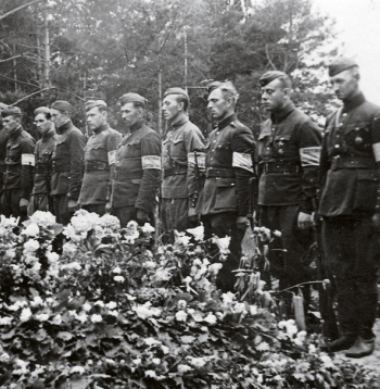 Bijušo Latvijas armijas karavīru un aizsargu – tobrīd Vācijas kārtības
dienesta darbinieku ierinda  pie padomju okupācijas Baigā gada
upuru masu kapa. 1941. gada vasara.