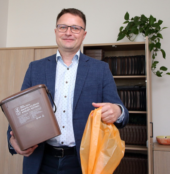 Pašvaldībā var saņemt gan kastīti, gan arī oranžas krāsas maisiņus, tos var pirkt arī veikalā, kurus pēc piepildīšanas aizsien un met nešķiroto atkritumu konteinerā. Viļņas pašvaldības Enerģētikas departamenta vadītājs Daliuss Krinicks demonstrē mājsaimniecībām izsniedzamās kastītes un maisiņus.