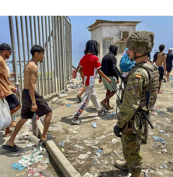 Spānijas karavīrs noraugās, kā no Marokas puses atpeldējušie migranti 31. jūlijā ierodas Seutā.