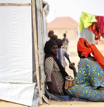 Sievietes sēž pie pagaidu telts iekšzemē pārvietoto personu (IDP) nometnē Maiduguri pilsētā Nigērijas ziemeļaustrumos, 2021. gada 19. martā. Vairāk nekā desmit gadus ilgajā "Boko Haram" krīzē Nigērijas ziemeļaustrumos īpaši cietušas sievietes un bērni, kuri kļuvuši par nolaupīšanu, piespiedu pievēršanas islāmam, fiziskas un psiholoģiskas vardarbības, piespiedu darba un piespiedu laulību upuriem. Lai gan "Boko Haram" vardarbība pret sievietēm un bērniem jau kopš grupējuma darbības sākuma ir pievērsusi starptautisku uzmanību, aizvien liels izaicinājums ir nodrošināt iekšzemē pārvietotajām personām aizsardzību un atbalstu ikdienas vajadzībām, ar ko saskaras daudzas palīdzības organizācijas.