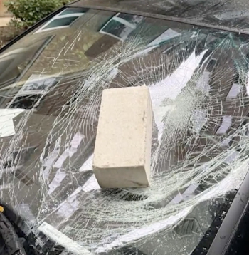 Ķieģelis piezemējies uz automāsīnas priekšējā stikla.