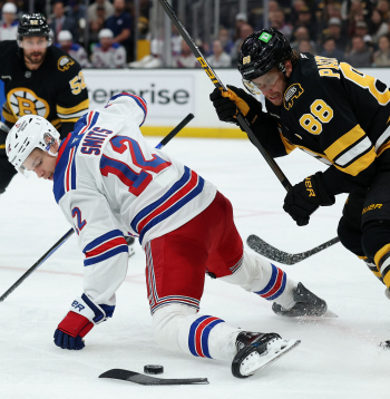 Alberts Šmits (no kreisās) arī ar salūzušu nūju un gandrīz jau uz ceļiem cenšas apturēt ripu, lai tā nenonāktu pie Bostonas "Bruins" kapteiņa Davida Pastrņāka.