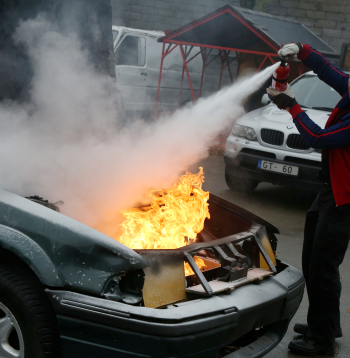 Degošas automašīnas dzēšana izmantojot ugunsdzēšamo aparātu. Ilustratīvs attēls. Degošas automašīnas dzēšana izmantojot ugunsdzēšamo aparātu. Ilustratīvs attēls.