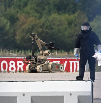 Kriminālistikas eksperts strādā līdzās policijas sapieru robotam pie Ukrainas kravas lidmašīnas Leipcigas/Halles lidostā Škeidicā, Vācijas austrumos, 2026. gada 5. augustā. Naktī lidmašīnas tuvumā tika atrasts ar sprāgstvielām aprīkots drons, bet netālu cita lidmašīna gaisā sadūrās ar nezināmu lidojošu objektu un pēc tam droši nolaidās.