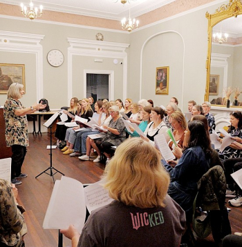 Londonas latviešu koris savā mājvietā – "Daugavas vanagu" fonda Londonas namā. Tur, kur zālē pie sienas piestiprināts Latvijas ģerbonis, vienmēr stāv diriģents.