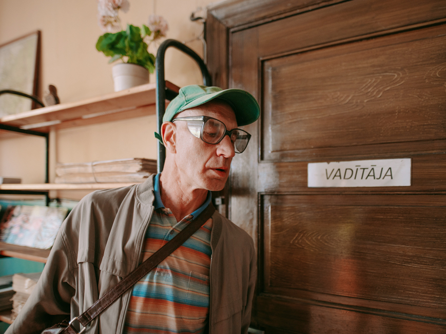 Skats no seriāla “Pilna pastkaste”. Ģirta Krūmiņa pastnieks Pēteris Brīniņš nesmādē arī noklausīties iegūtas ziņas.