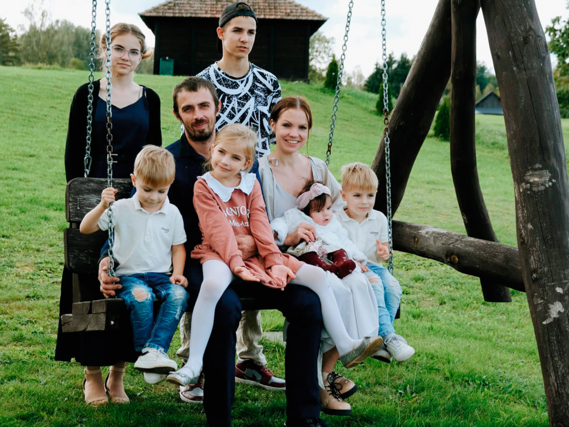 Ģimenes foto: šūpolēs sēž (no kreisās) Teodors, tētis Renārs ar meitu Tīnu klēpī, Zanda ar jaunāko meitiņu Gerdu, blakus Tālavs, aiz šūpolēm stāv vecākie bērni Viktorija un Tomass.