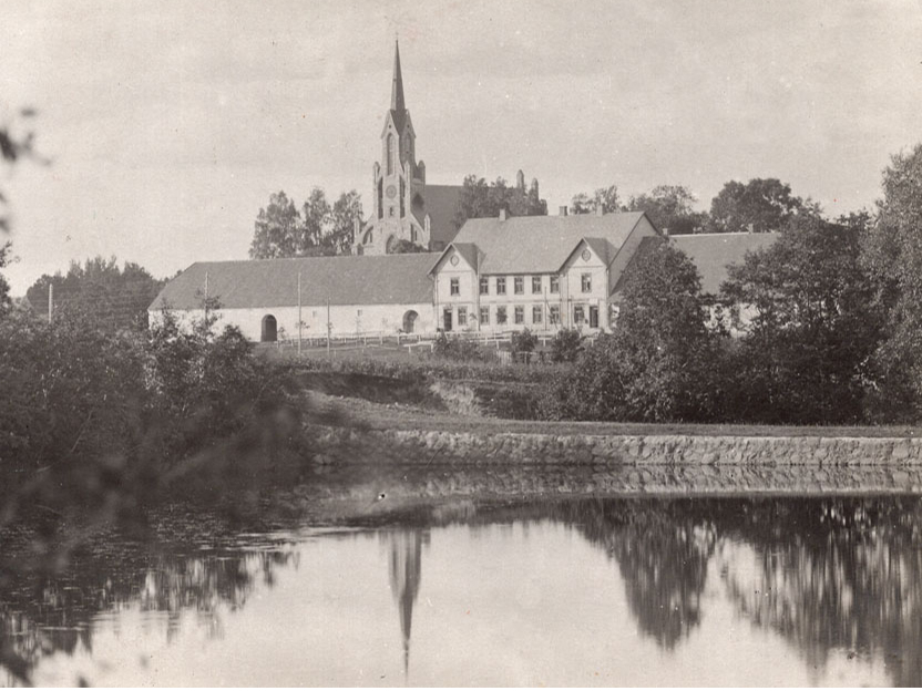 Cesvaines biedrības māja, priekšplānā dzirnavu dīķis, aizmugurē luterāņu baznīca. Fotografēts pirms 1916. gada rudens. Kreisajā pusē kroga stadula, kas pārbūvēta par kultūras veicināšanas biedrības zāli. Labajā pusē jau pirms simt gadiem bijuši veikali.