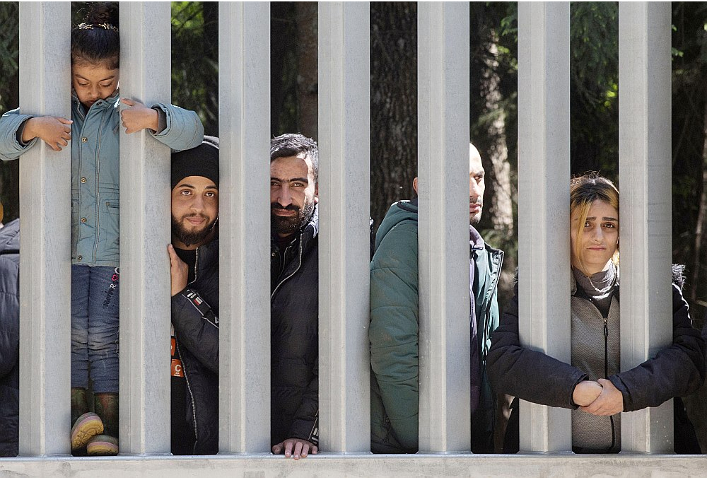 Trīsdesmit ļaužu grupa, kas cer saņemt patvērumu Polijā, aiz jaunuzbūvētās sienas migrantu plūsmas apturēšanai pie Belovežas 2023. gada maijā.