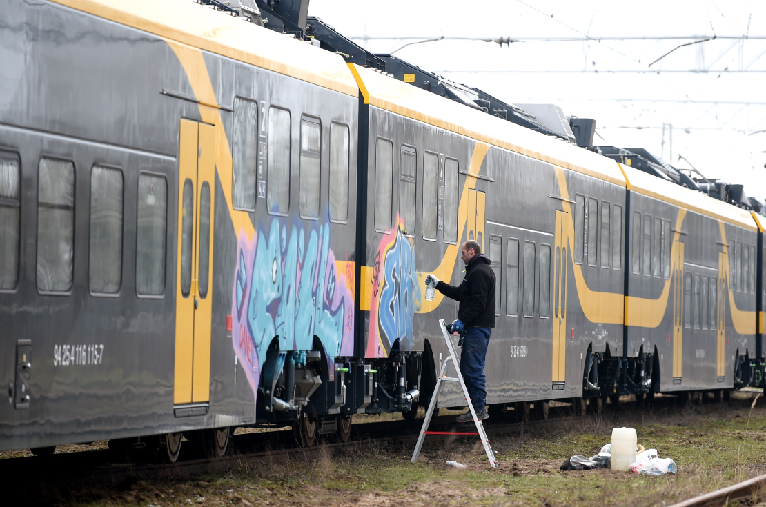 Vīrietis mazgā ar grafiti apķēpātu jauno "Škoda Vagonka" elektrovilcienu Vagonu depo.