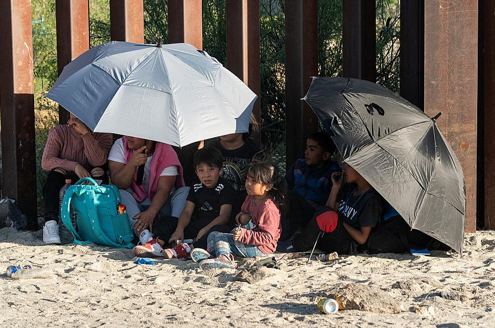 Migranti jau pēc Meksikas un ASV robežas šķērsošanas pie robežas žoga gaida Savienoto Valstu robežsargus.