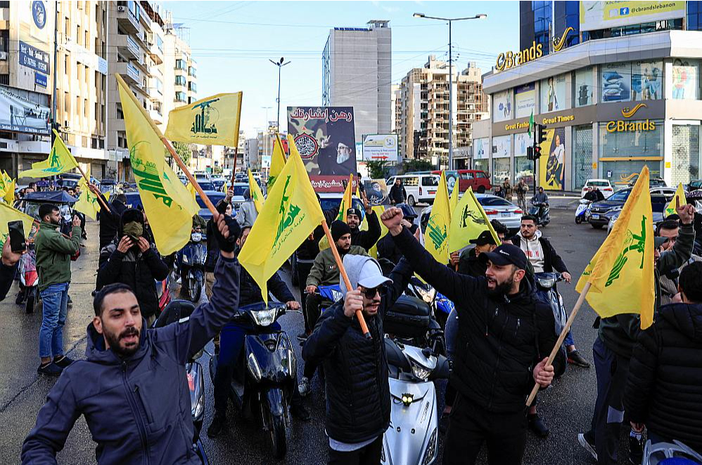 "Hezbollah" atbalstītāji ar šī grupējuma karogiem rokās Beirūtas dienvidu pievārtē svin pamiera stāšanos spēkā.