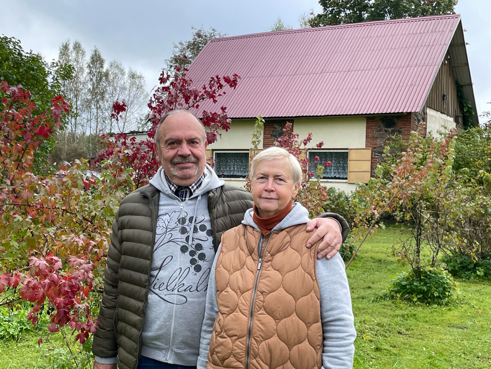 Aija Dzintra un Dainis Paukšēni 20 gados spējuši iekopt bagātīgu
ogulāju dārzu, kurā aug un ražo arī neparastāki augi. Attēlā: saimnieki savā dārzā, aiz muguras redzama māja, kurā ierīkota telpa ekskursantu grupu uzņemšanai.