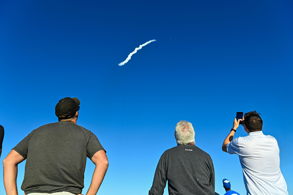 Cilvēki vēro, kā “Blue Origin” raķete “New Glenn” paceļas no 36. palaišanas kompleksa savā otrajā palaišanas mēģinājumā Kanaveralas Kosmosa spēku stacijā 2025. gada 13. novembrī, Floridā. “New Glenn” otrā misija NG-2 nogādā uz Marsu NASA dvīņu kosmosa zondes “ESCAPADE”, bet uz borta atrodas arī “Viasat” tehnoloģiju demonstrators, kas paredzēts NASA Sakaru pakalpojumu projekta atbalstam.