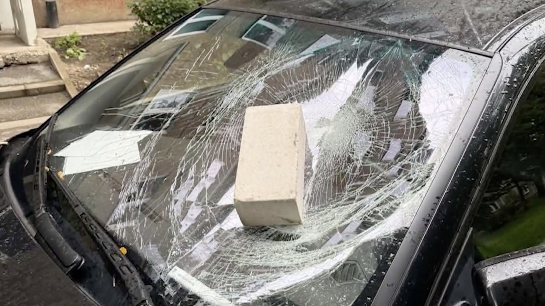 Ķieģelis piezemējies uz automāsīnas priekšējā stikla.