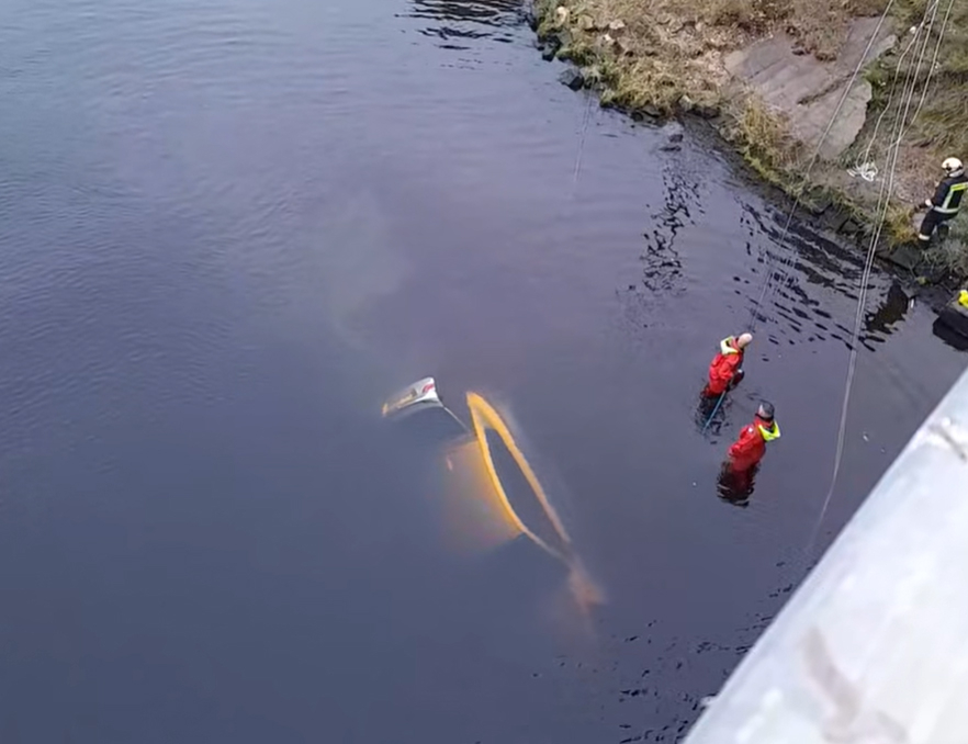 Zem tilta pār Mīlgrāvi ūdenī iebraukusi automašīna.