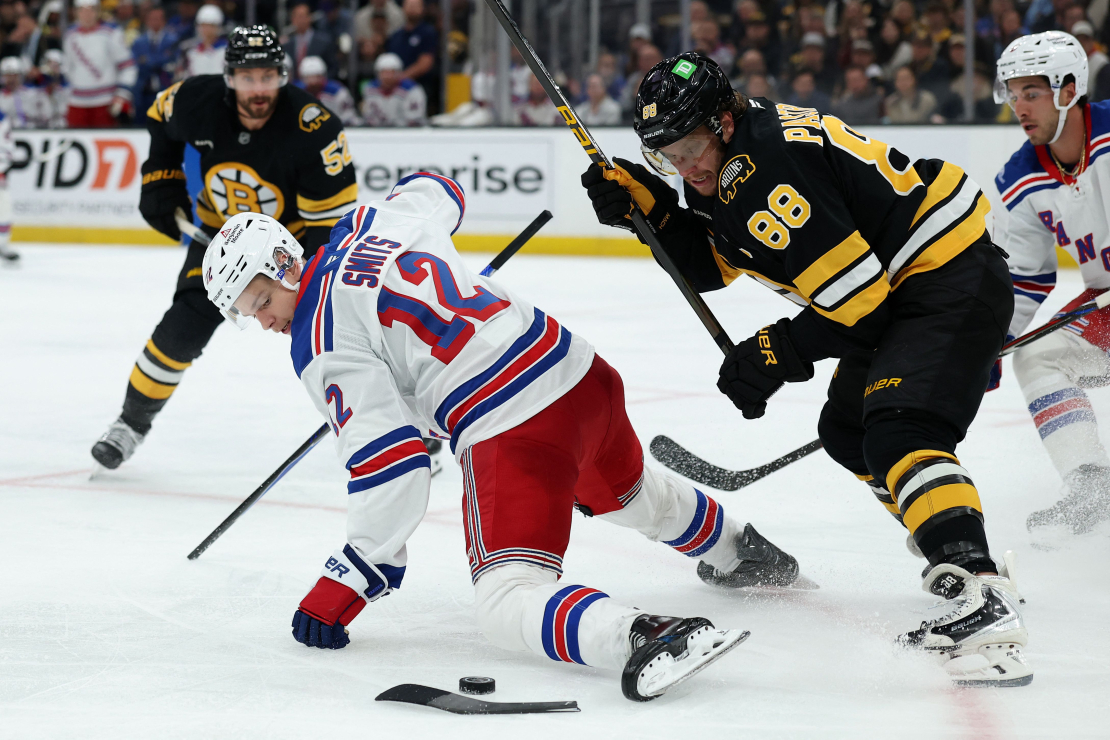 Alberts Šmits (no kreisās) arī ar salūzušu nūju un gandrīz jau uz ceļiem cenšas apturēt ripu, lai tā nenonāktu pie Bostonas "Bruins" kapteiņa Davida Pastrņāka.