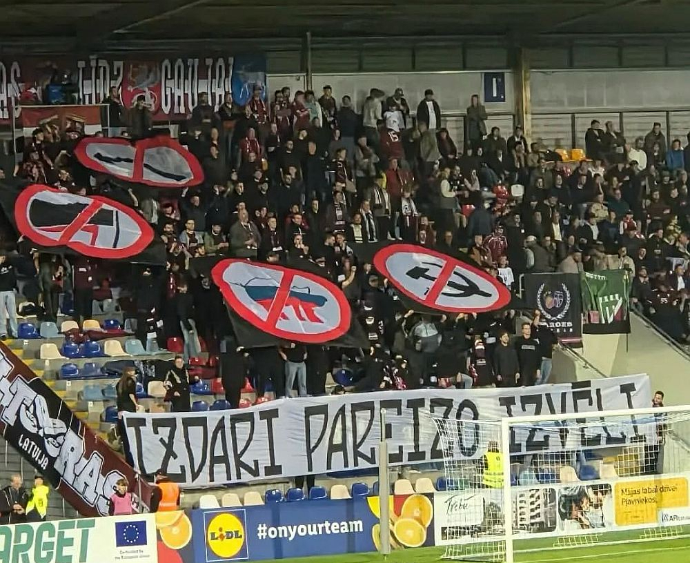 Latvijas futbola izlases fani aicināja piedalīties Saeimas vēlēšanās un izdarīt pareizo izvēli, ar četriem simboliem norādot virzienu – nebalsot par prokremliskiem spēkiem, komunistiem un kreiso ideju virzītājiem. Kreisajā pusē attēlotais ir antifa simbols, kas Eiropā izplatīts arī futbola ultru vidū, tas nozīmē iestāšanos pret galēji labējām un neonacistiskām idejām. Plakāti tribīnēs bija redzami vairāk nekā piecas minūtes un sociālajos tīklos ieguva gana lielu popularitāti.