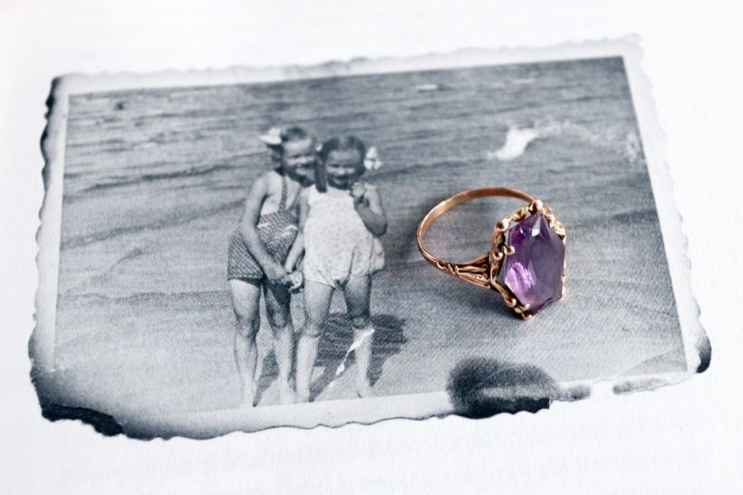 Māras Celles gredzens ar ametistu, novietots uz viņas autobiogrāfiskās grāmatas ″Meitene no Mežaparka″ lappuses, kurā redzama fotogrāfija ar apgruzdušām maliņām.