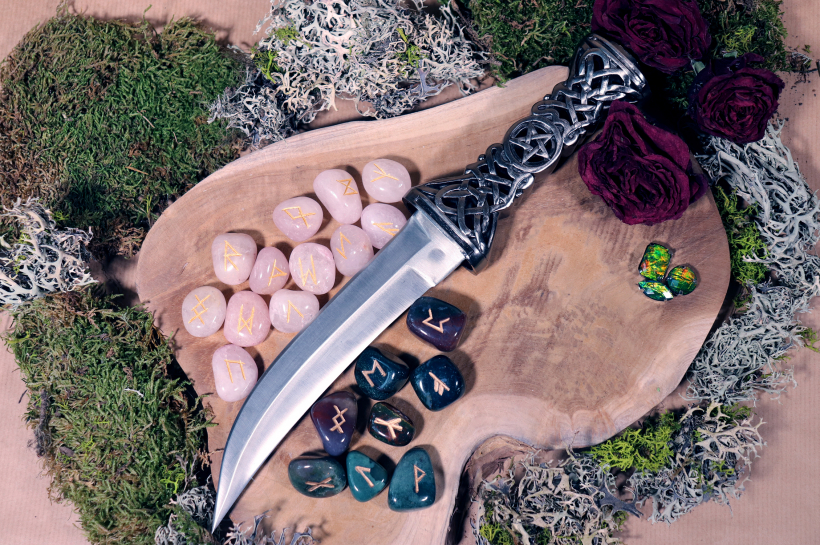 Svētais Athames duncis ar rūnām, kas izgatavotas no rozā kvarca un asinsakmens, gatavs burvības rituālam.