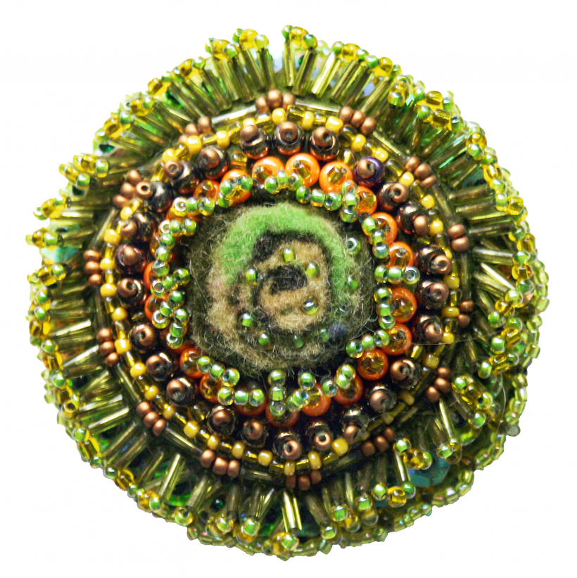 Brošiņa ir darināta tērpam piemērotā tonī no dažāda izmēra pērlītēm uz filca pamata.