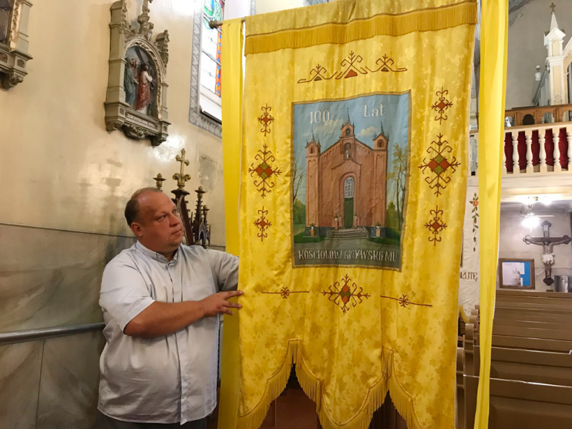 Priesteris Vjačislavs Rosļaks demonstrē procesiju karogu, kas tapis par godu baznīcas simtgadei astoņdesmito gadu beigās.