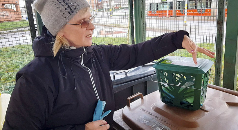 Daudzdzīvokļu nama vecākā Tatjana Antonova izrāda komplektu, ko saņēma katrs mājas iedzīvotājs, lai varētu iesaistīties bioloģisko atkritumu šķirošanas pilotprojektā – vaļēju groziņu un maisiņus, kas gatavoti no kukurūzas un sadalās tāpat kā tajos ievietotie bioloģiskie atkritumi.